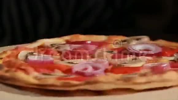 新鲜出炉的意大利辣香肠蘑菇洋葱和胡椒粉的比萨饼转过来正面观点视频的预览图
