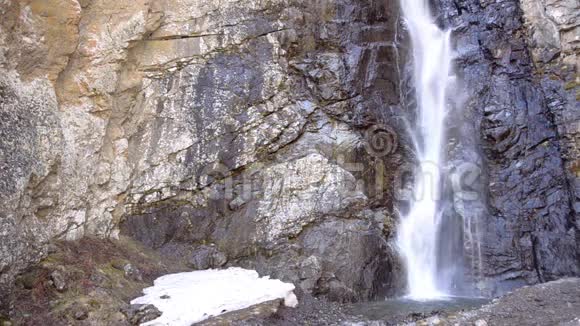 狭窄的山瀑被岩石和未熔化的雪包围小瀑布格鲁吉亚高加索视频的预览图