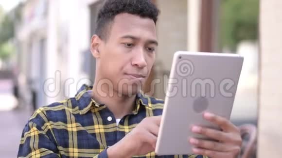 非洲青年男子使用平板户外视频的预览图