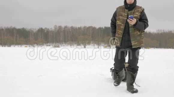 一个带着电话在冰冻湖上寻找理想路线的年轻人他拉着雪橇的东西视频的预览图