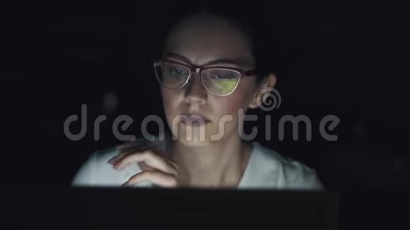 用眼镜反射屏幕一个商务女性在笔记本电脑上工作到很晚的肖像视频的预览图