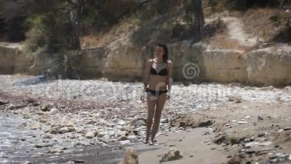 一个穿着黑色比基尼在海滩散步的美女视频的预览图