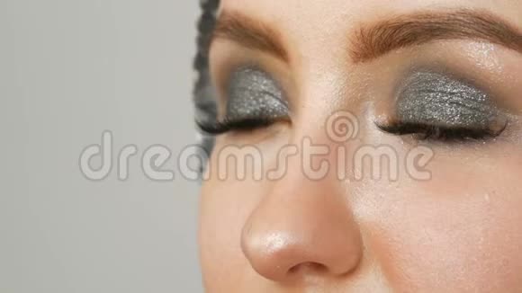 化妆师用特殊的画笔灰色眼影女孩的眼睛和睫毛制作出烟熏眼视频的预览图