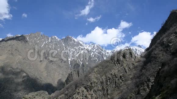 轻盈的白云浮在高高的崎岖的山巅上积雪残留高加索格鲁吉亚视频的预览图