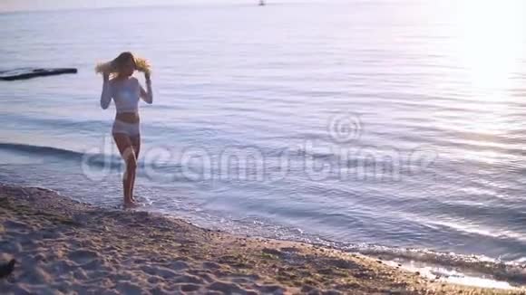 那个女孩在日落时沿着海滩散步注意力不集中有利于背景慢动作视频的预览图