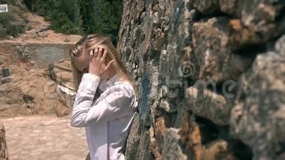 美丽的女孩在石头面前摆姿势微笑视频的预览图