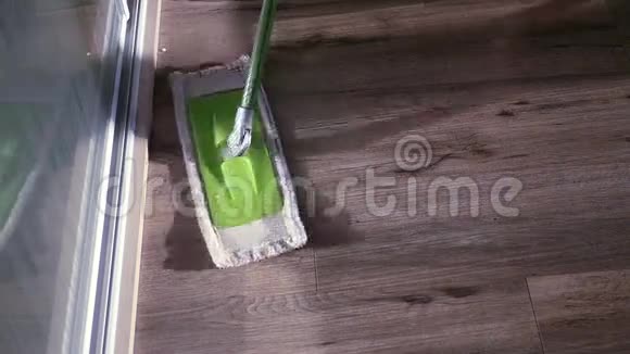 一个绿色的拖把从橱柜附近的地板上清除污垢慢动作视频的预览图