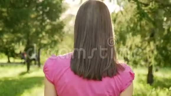 波夫无忧无虑开朗的黑发女郎在公园散步放松暑假后面的摄像头视频的预览图