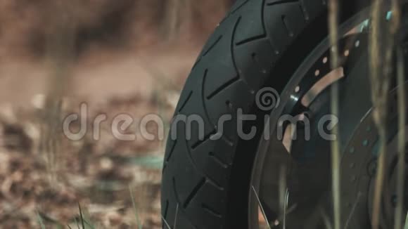 摩托车车轮橡胶轮胎在土路上草地在风中摇动视频的预览图