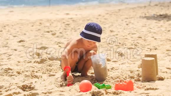 帽蹲小男孩在海边做沙蛋糕视频的预览图