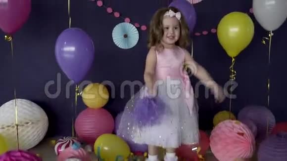 一个漂亮的小女孩在她的生日聚会上笑着玩视频的预览图