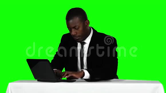 商人坐在办公桌前用笔记本电脑办公室工作绿色屏幕视频的预览图