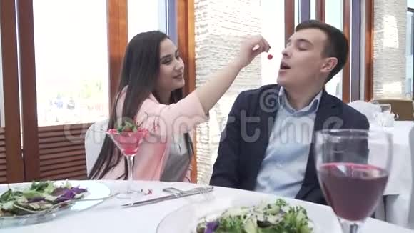 一对情侣在餐馆吃晚饭一个女孩正在给一个男人喂浆果视频的预览图