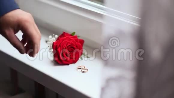 新郎拿着结婚戒指和花为庆祝活动做准备特写镜头视频的预览图