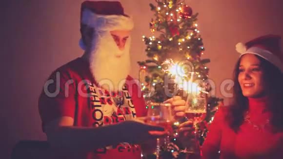 年轻的帅哥和美女戴着圣诞帽迎接新年喝着香槟点燃着火花视频的预览图