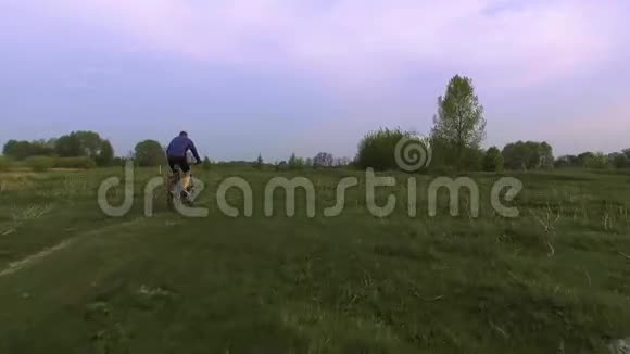 骑自行车的人骑在春绿的草地上视频的预览图