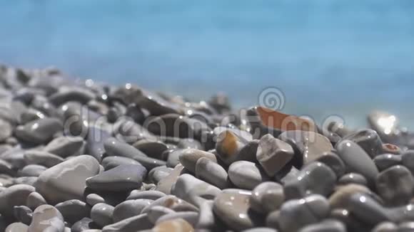 海上冲浪者正在飞溅鹅卵石海滩波浪在多种颜色的抛光石和卵石上移动近距离观看慢慢慢慢视频的预览图