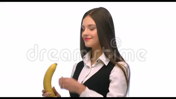 美丽的黑发商务女性白色背景下拿着香蕉视频的预览图