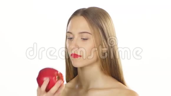 戴着牙套的金发女孩吃着一个大红苹果白色的特写视频的预览图