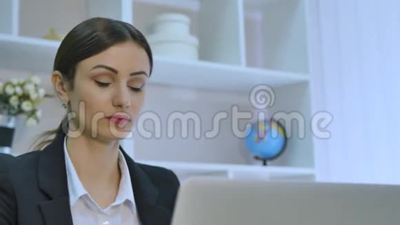 疲惫的女商人在明亮的办公室里用笔记本电脑时头痛视频的预览图