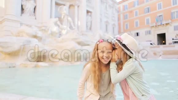可爱的小女孩坐在罗马的特雷维喷泉边上窃窃私语快乐的孩子喜欢欧洲视频的预览图