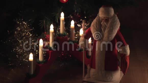圣诞老人的老式旧玩具站在电烛台和圣诞树旁视频的预览图