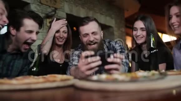 一群快乐的朋友在咖啡馆里看着电话里的照片笑着视频的预览图
