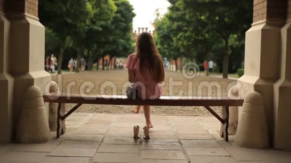 十几岁的女孩坐在大自然的长凳上赤脚阅读一本双腿交叉的书背面视频的预览图