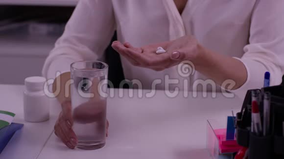 女性手拿着一杯水和药片女人手拿药丸药片和一杯水治疗头痛视频的预览图