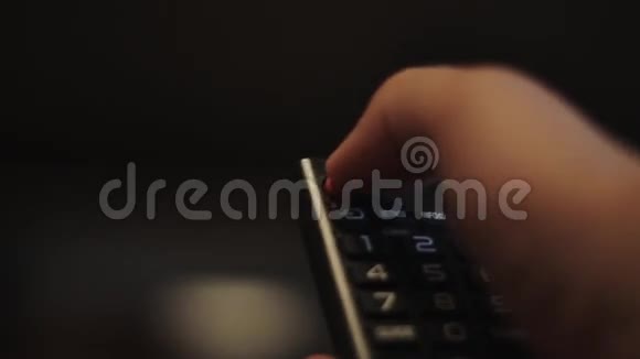 人类的手在黑色电视遥控器上按下按钮视频的预览图