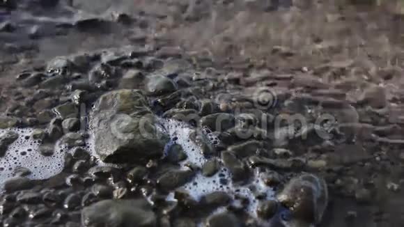 石头被河水冲刷平静的波浪形成泡沫视频的预览图