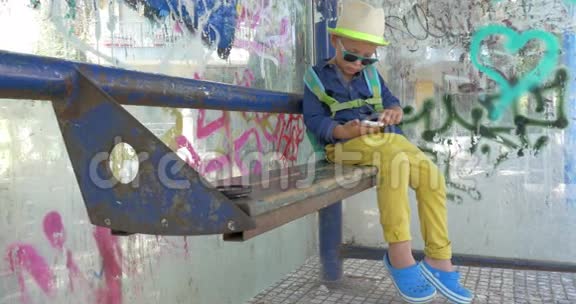 儿童使用智能手机在肮脏的公共汽车站视频的预览图