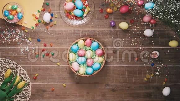人们从装饰着复活节彩蛋的桌子上拿着一篮子复活节彩蛋顶部视图视频的预览图