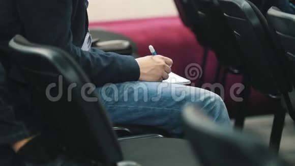 学生在礼堂用钢笔在笔记本上写字合上视频的预览图