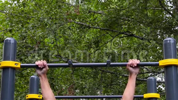 运动员在城市公园的水平杆上做拉力运动前面的风景健身视频的预览图