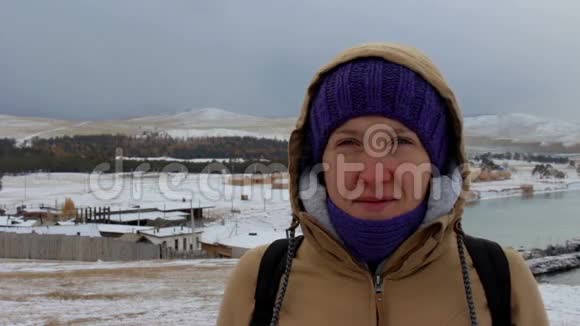 一个穿着夹克头罩在海上的微笑女孩的肖像视频的预览图