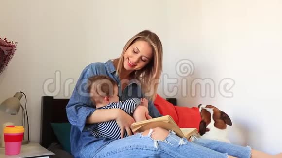 年轻的母子和一只狗坐在床上视频的预览图
