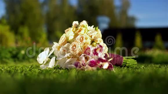 新娘的一束白色玫瑰和浆果放在绿草上视频的预览图