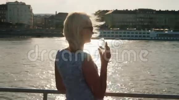 一个女人拿着一杯香槟在船上航行以多瑙河为背景的多瑙河游船视频的预览图