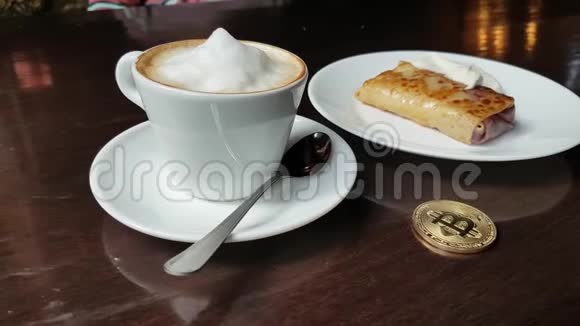 卡布奇诺煎饼与酸奶油和比特币金币在桌子上的咖啡馆全景从左到右视频的预览图