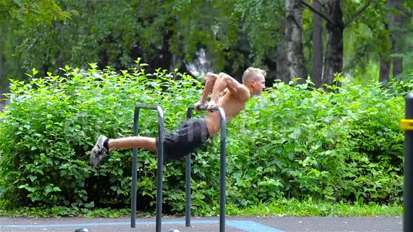 在城市公园的酒吧里做俯卧撑的运动员侧视健身视频的预览图