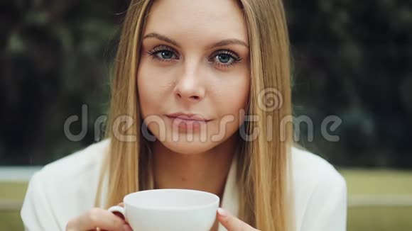 可爱的年轻女子坐在咖啡馆里喝咖啡视频的预览图