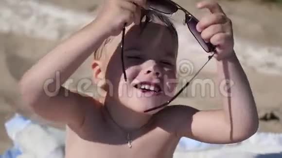 这孩子试着戴太阳镜海滩阳光明媚的热天视频的预览图