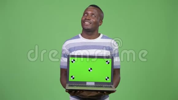 年轻快乐的非洲男人一边思考一边展示笔记本视频的预览图