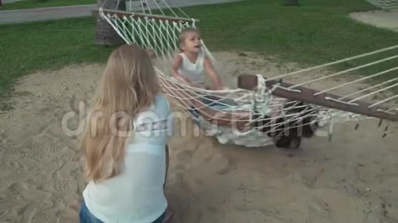 快乐妈妈摇着女儿吊床慢动作股票录像视频的预览图