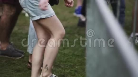 年轻的金发女郎穿着牛仔短裤在露天音乐会的人群中跳舞视频的预览图
