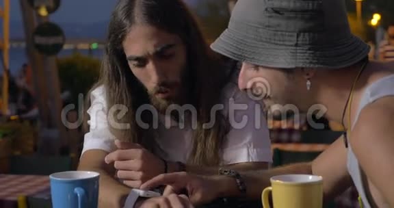 两个朋友在街边咖啡馆用智能手表视频的预览图