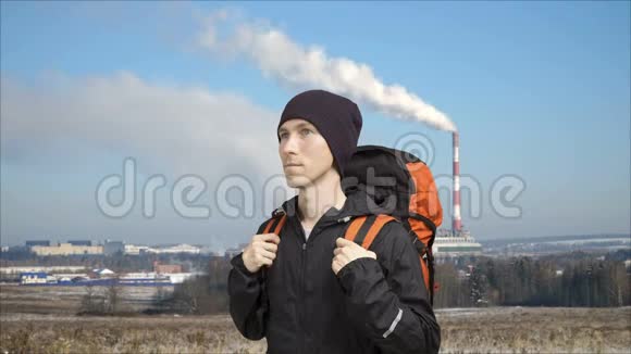 工厂的烟斗和前景中背包的人循环视频电影摄影视频的预览图