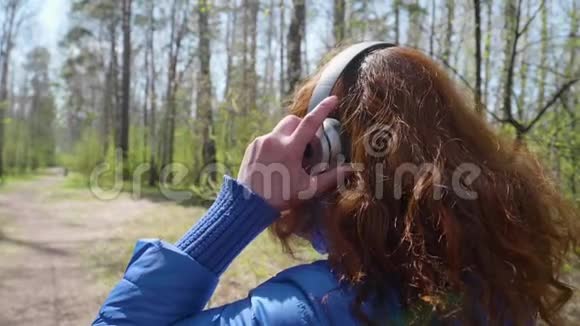 公园里的一个年轻女孩戴着耳机听音乐一个女人参加运动喜欢耳机里的音乐视频的预览图