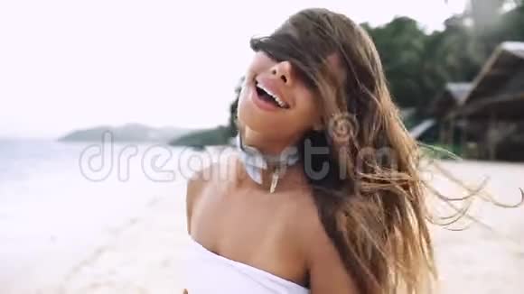 女孩带着美丽的微笑和长发在海滩上笑着跑步视频的预览图